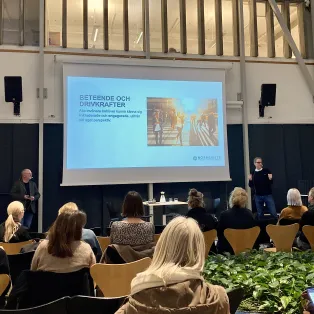 A person presenting in front of an sitting audience at the city library in Lund. Photo.